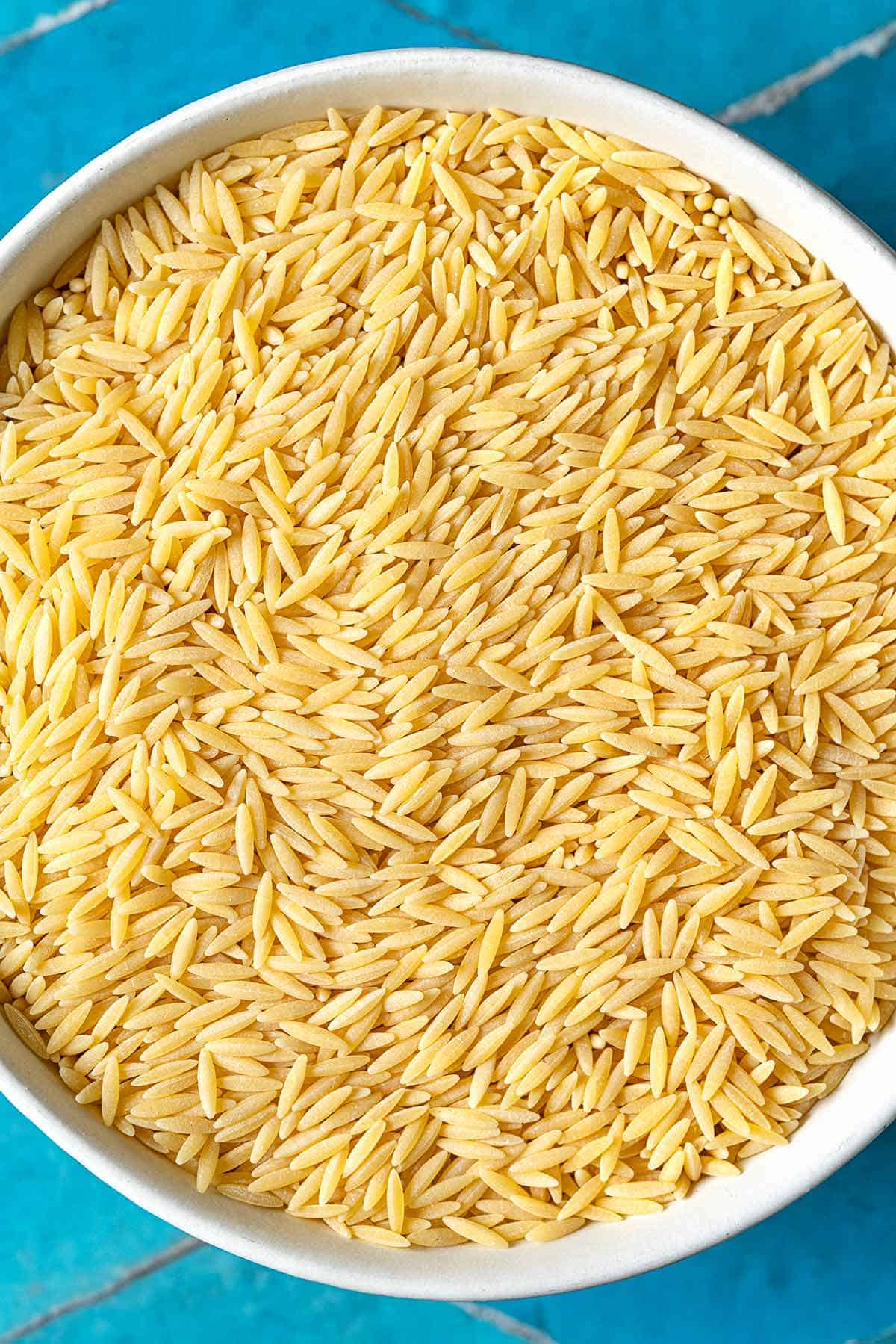 Uncooked orzo pasta in a bowl.