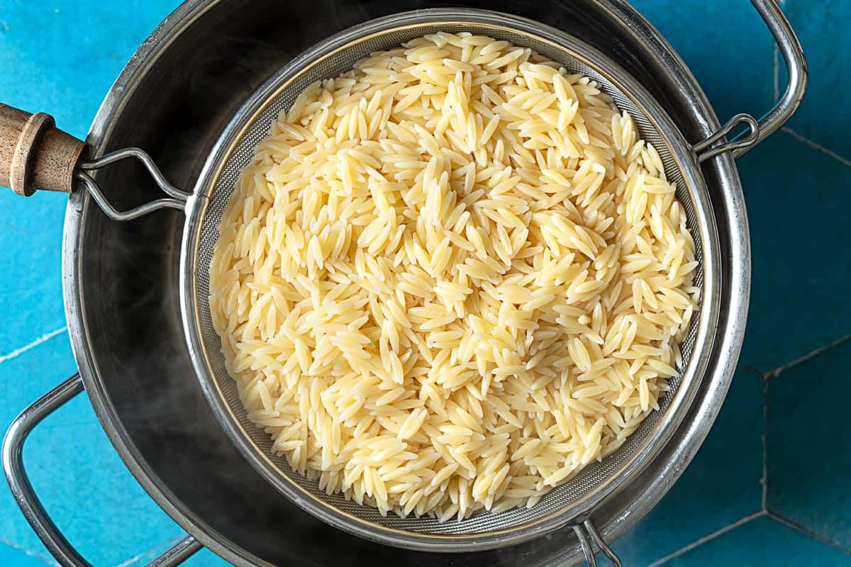 Cooked orzo in a strainer over a large pot.