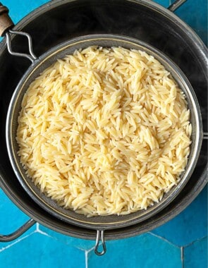 Cooked orzo in a strainer over a large pot.