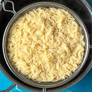 Cooked orzo in a strainer over a large pot.