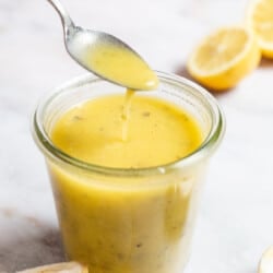 A spoonful of lemon vinaigrette being lifted from a jar of lemon vinaigrette.