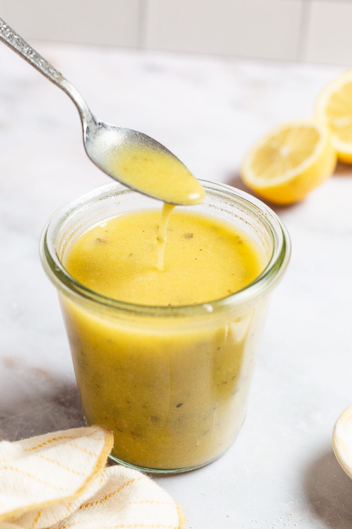 A spoonful of lemon vinaigrette being lifted from a jar of lemon vinaigrette.