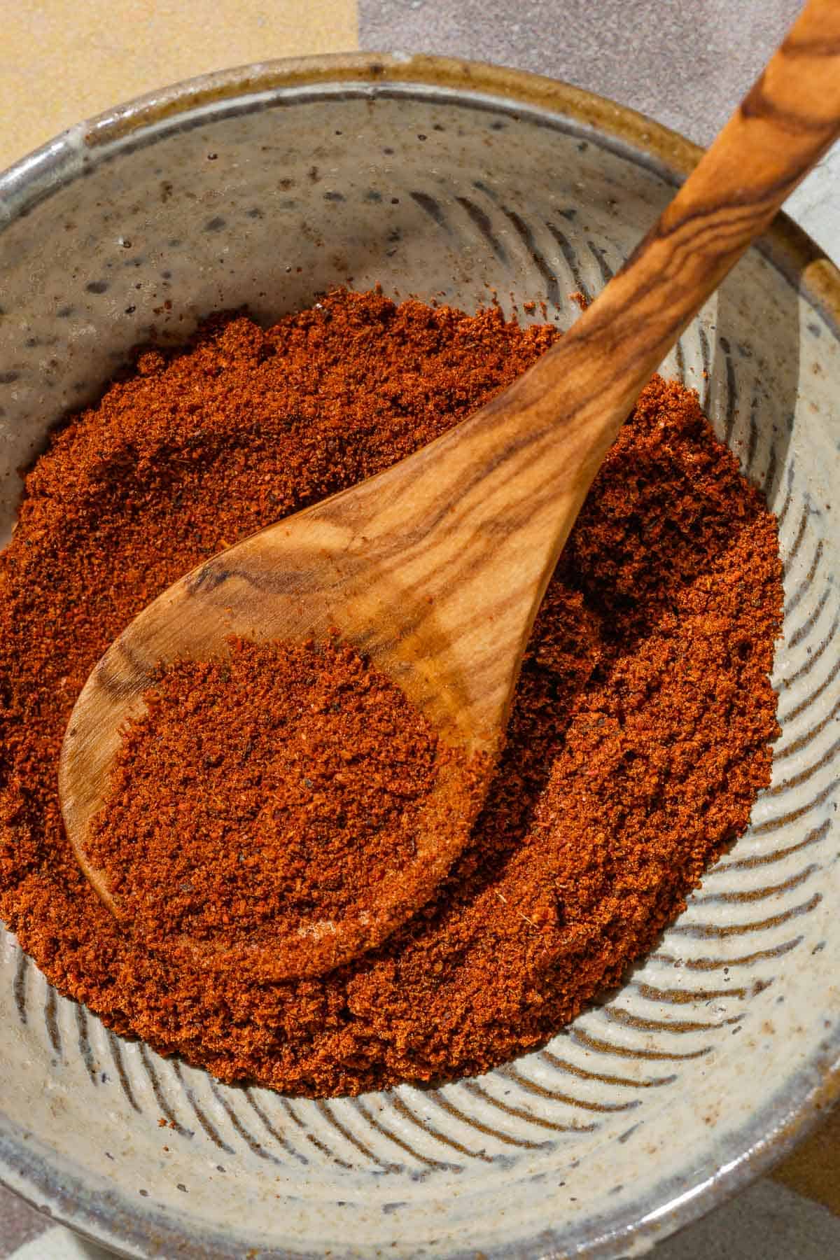 Baharat spice blend in a bowl with a small wooden spoon.