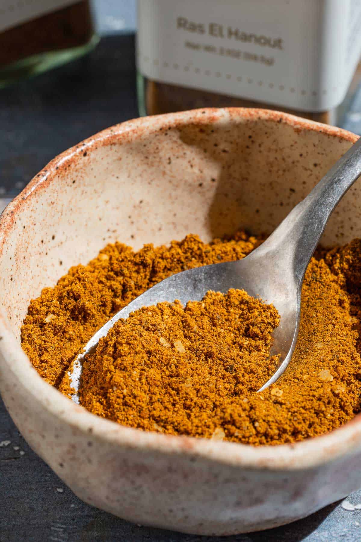 A close up of ras el hanout in a bowl with a spoon.