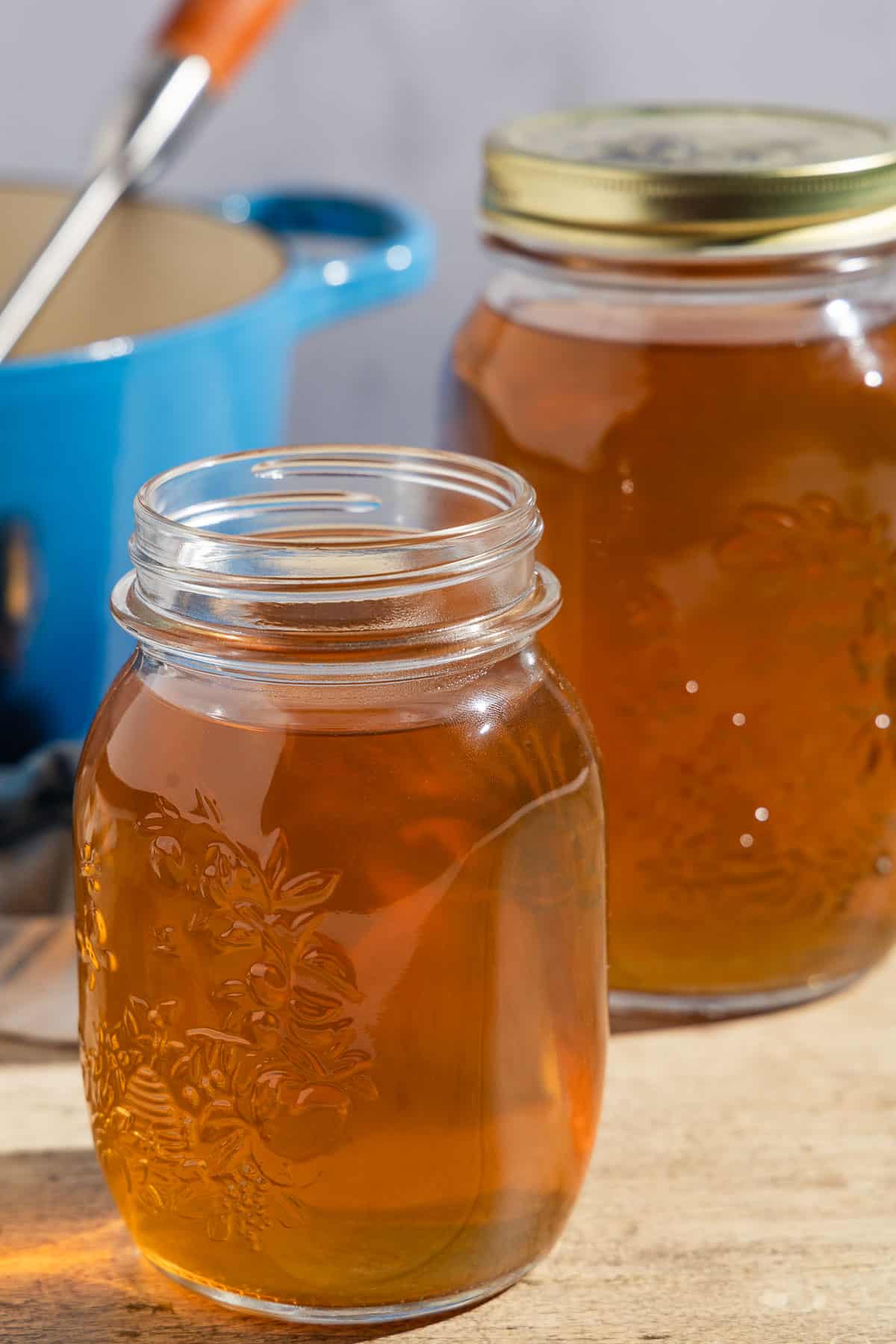 Two jars filled with homemade vegetable stock, one with a lid.