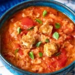 A close up of one bowl of pappa al pomodoro garnished with pieces of ciabatta bread and basil.