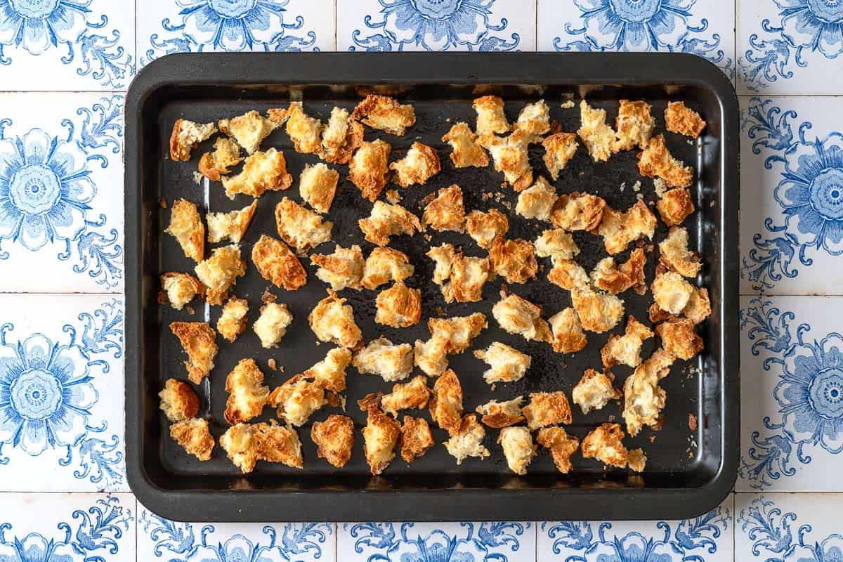 Pieces of toasted ciabatta bread on a baking sheet.