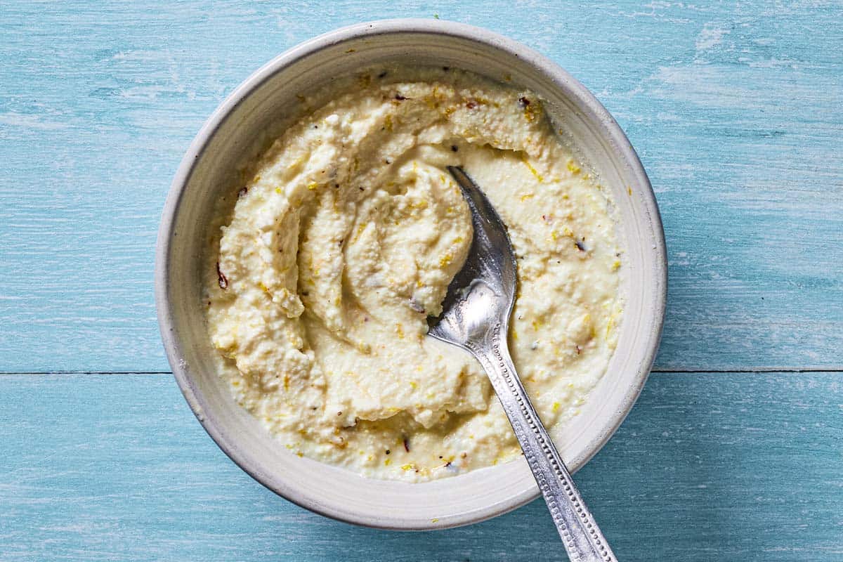 Lemon ricotta sauce in a bowl with a spoon.
