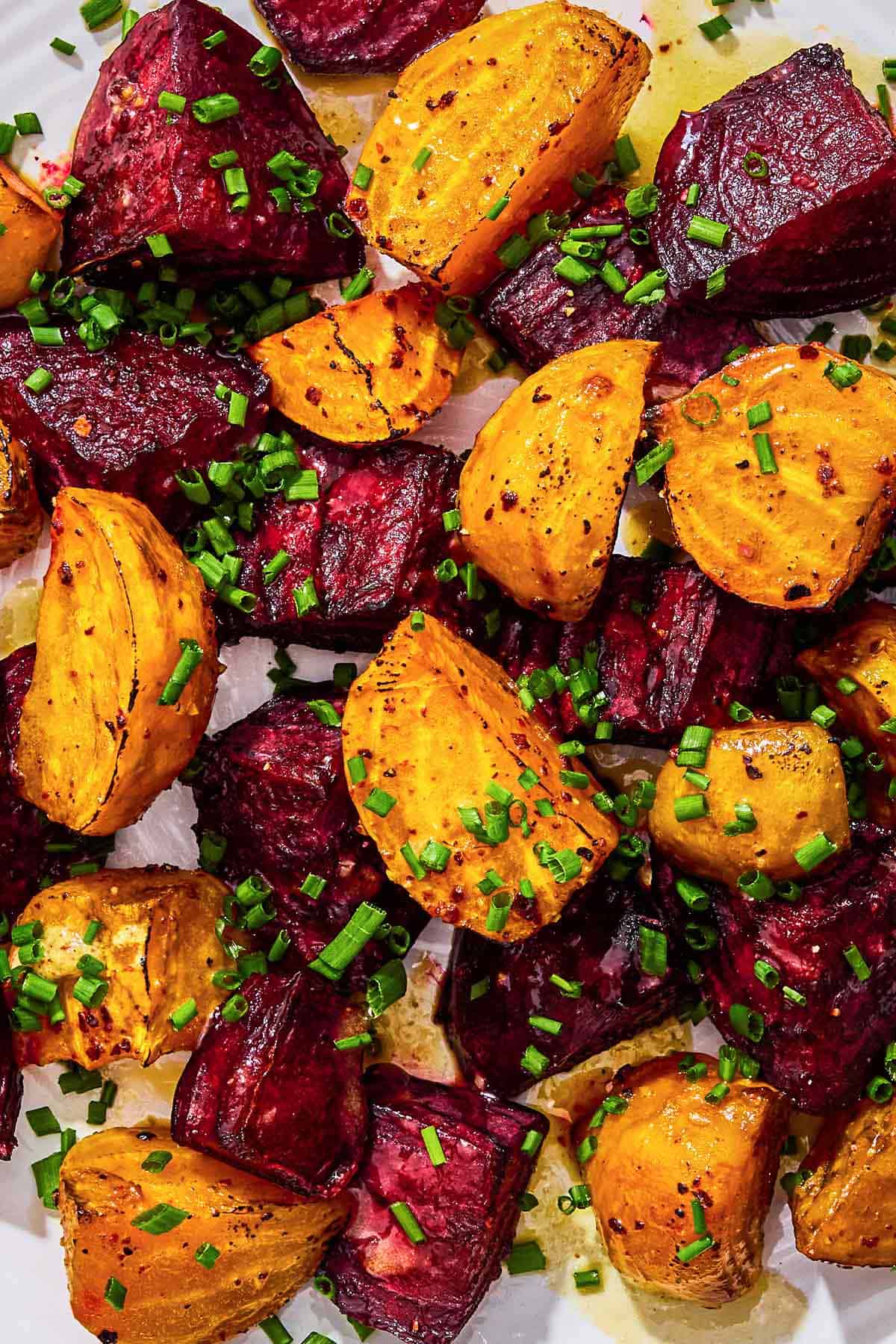 A close up of roasted beets topped with chives and a drizzle of apple cider vinaigrette.