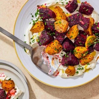 An overhead photo of roasted beets on a layer of labneh spread on a platter and topped with chives and a drizzle of apple cider vinaigrette with a serving spoon. Next to this is a serving of the roasted beets on a plate.