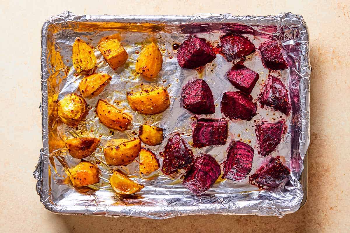 Seasoned roasted cubes of beets on a foil lined baking sheet.