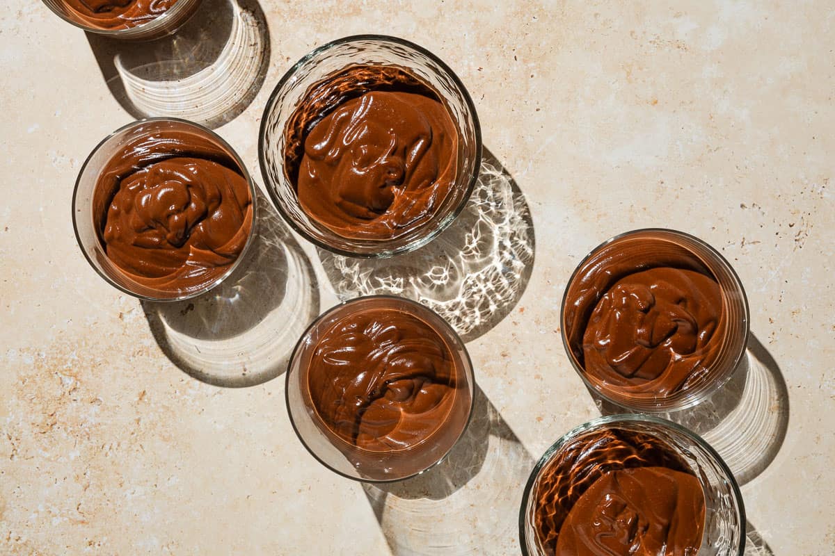 An overhead photo of 6 bowls of vegan chocolate pudding.