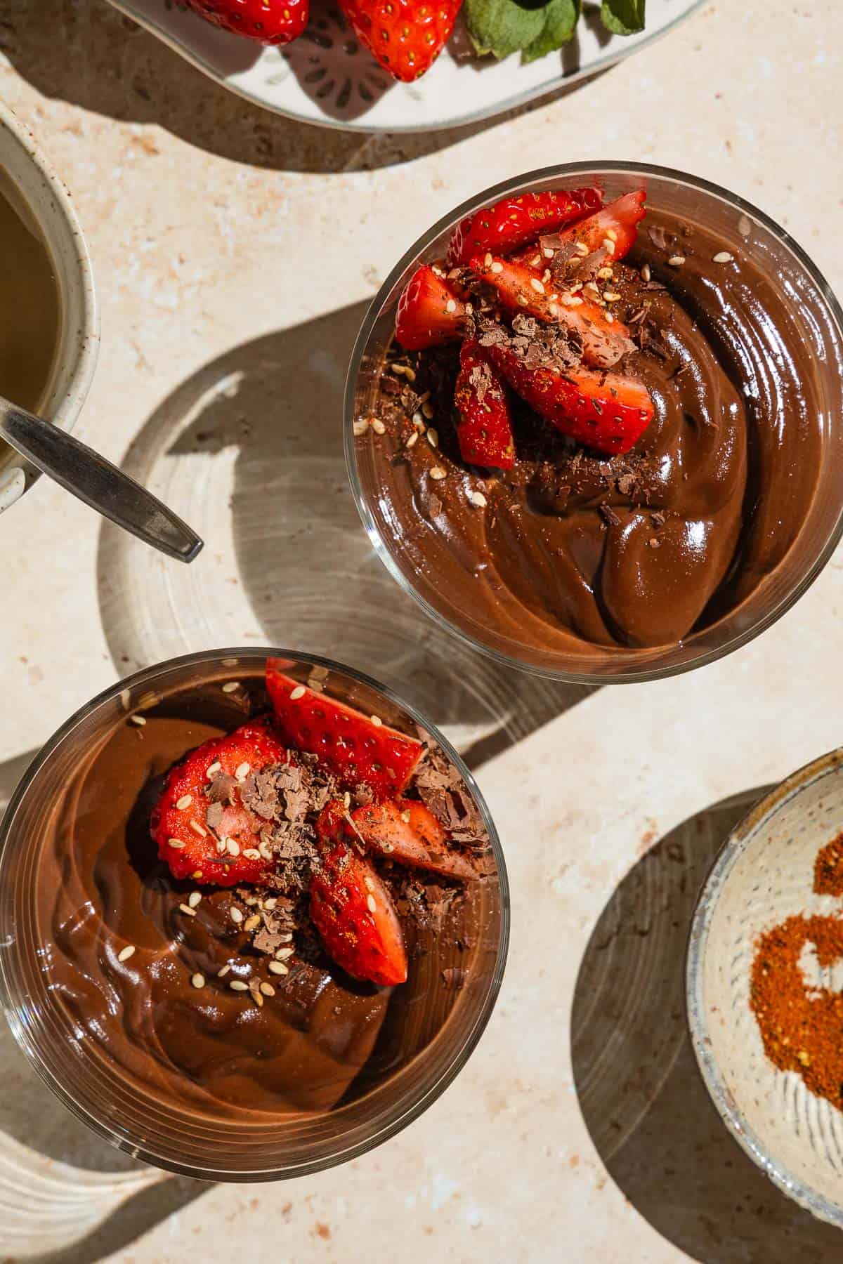 An overhead photo of two bowls of vegan chocolate pudding garnished with sliced fresh strawberries.