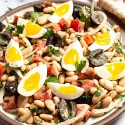 A close up photo of cannellini bean salad on a serving platter with a fork.