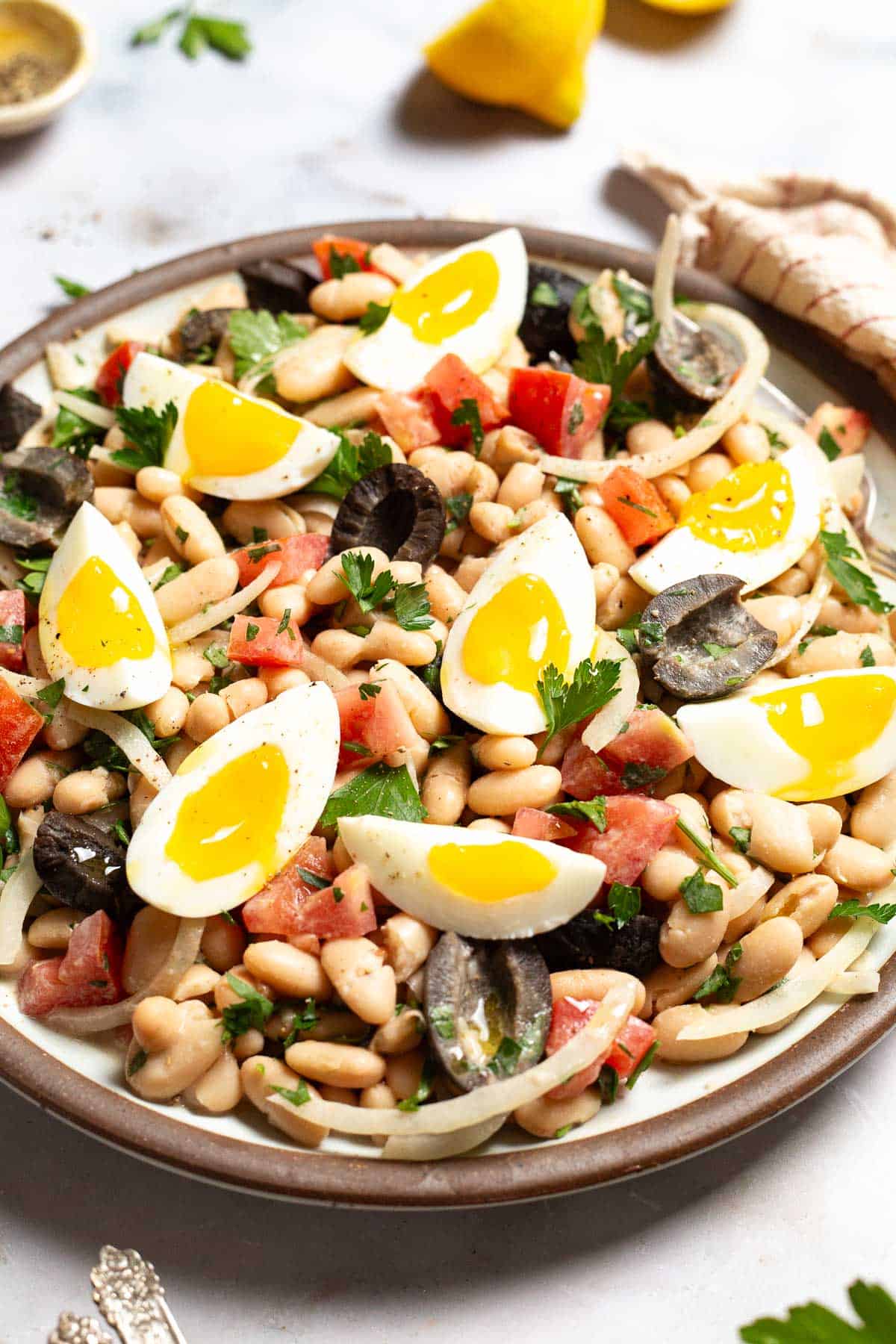 A close up photo of cannellini bean salad on a serving platter with a fork.