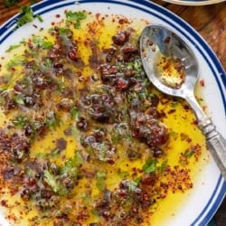 An overhead photo of bread dipping oil on a plate with a spoon.