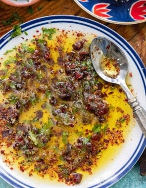 An overhead photo of bread dipping oil on a plate with a spoon.