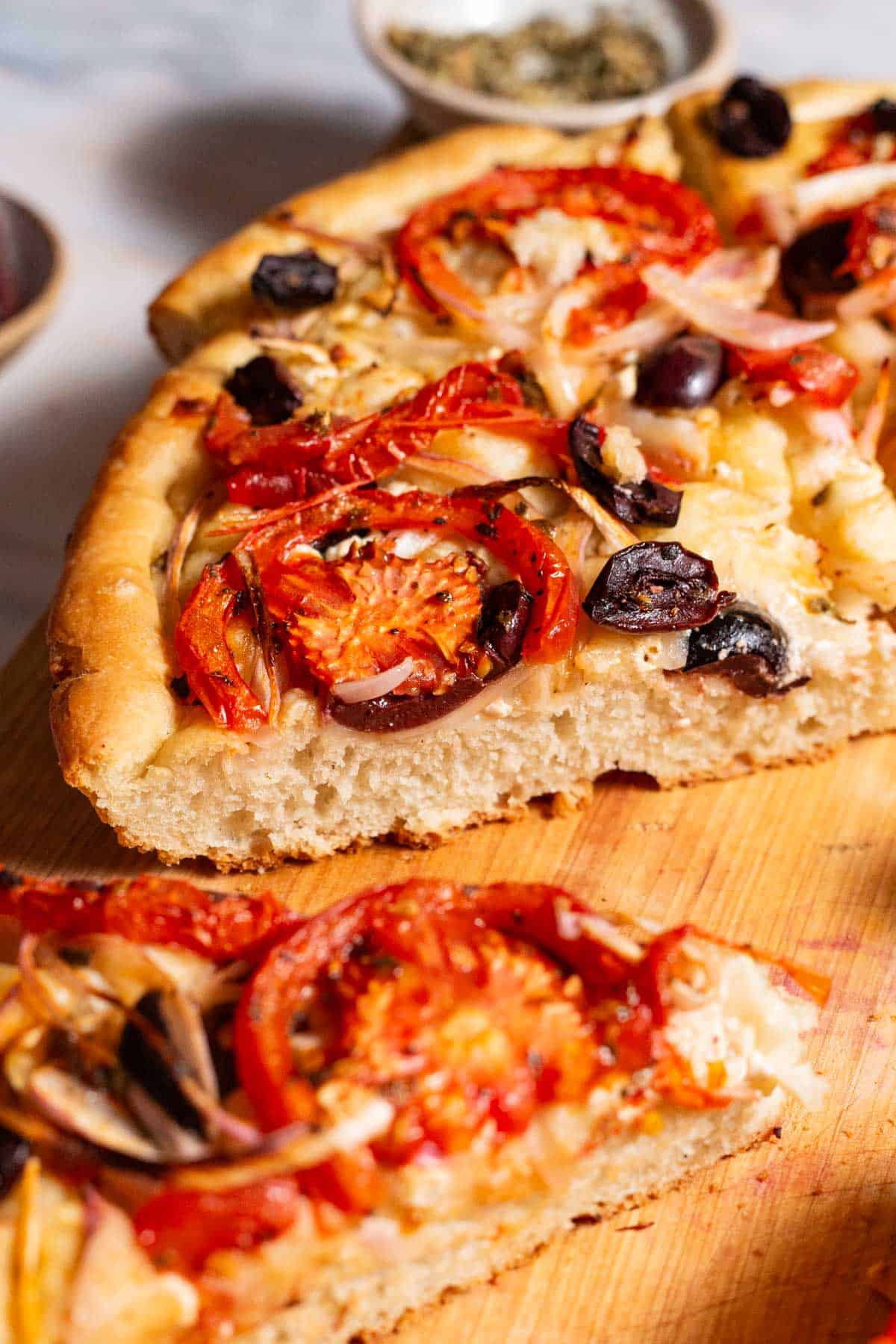 A close up photo of 4 slices of Greek pizza on a cutting board.