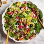 Italian salad in a serving bowl with wooden serving utensils. Next to this are bowls of salt, pepper, parmesan cheese and Italian seasoning. - 17