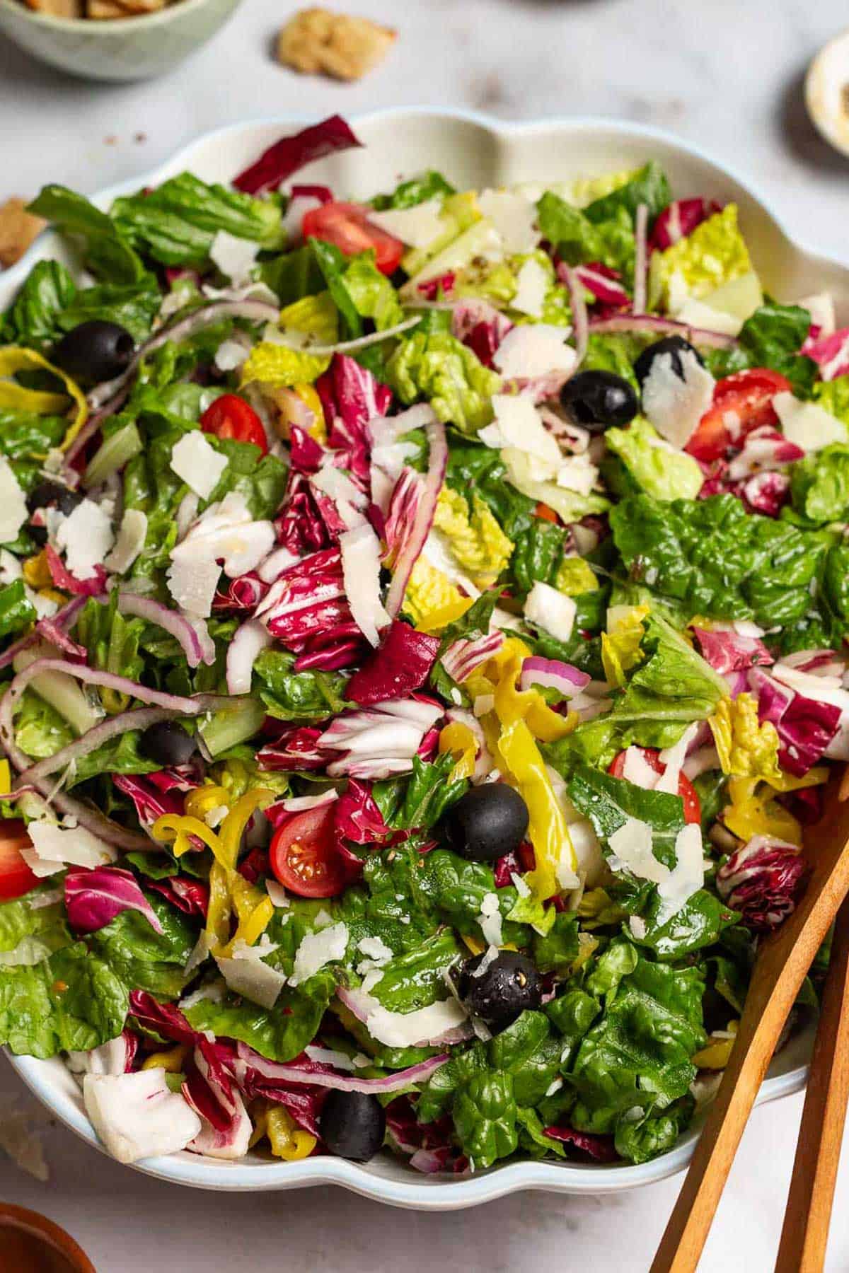 Italian salad in a serving bowl with wooden serving utensils.