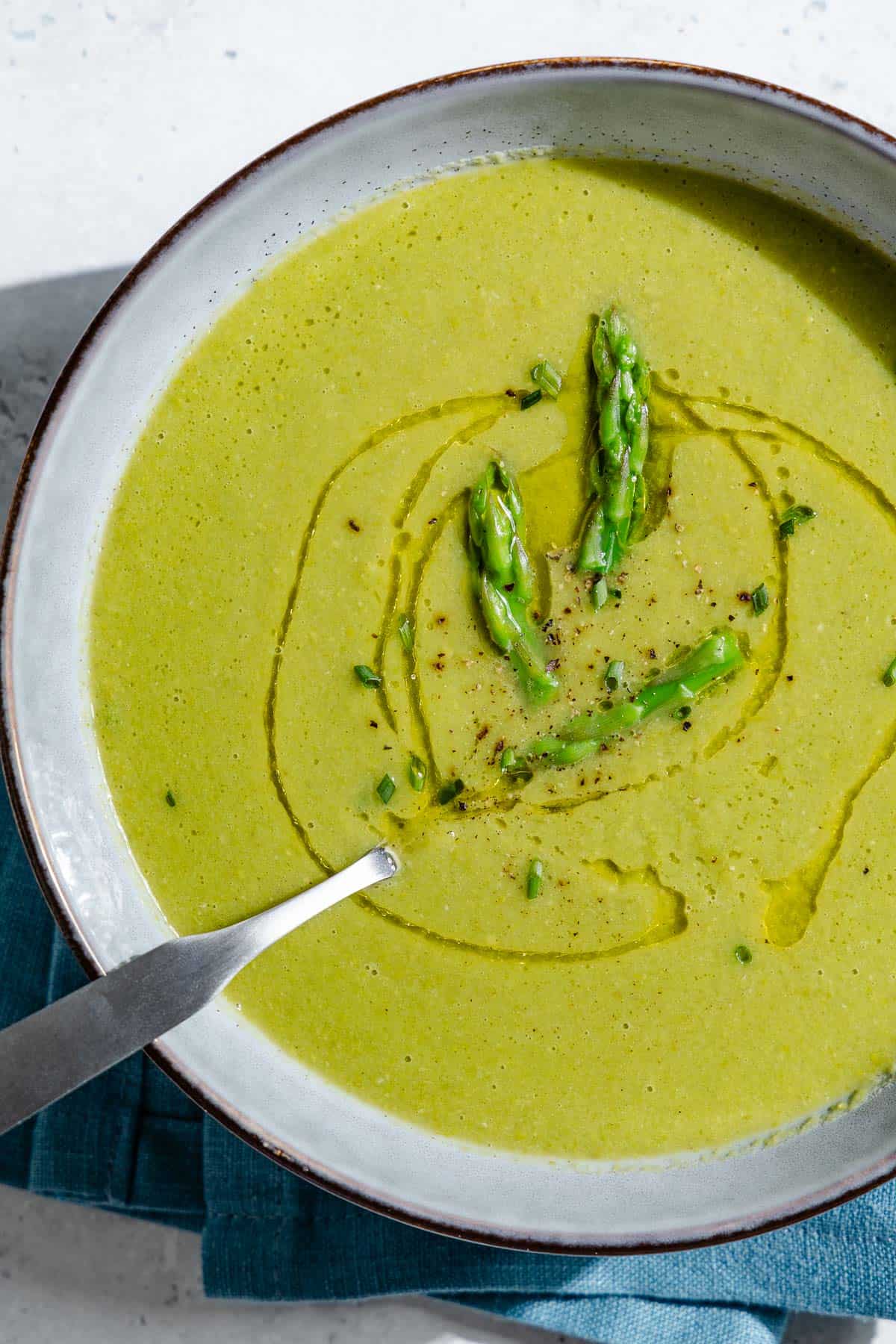 An overhead photo of a bowl of asparagus soup with a spoon.