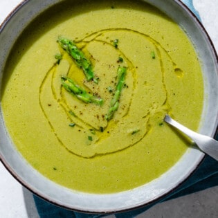 An overhead close up of asparagus soup in a bowl with a spoon.