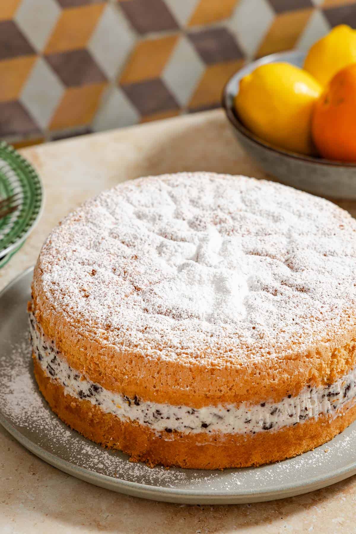 The easy cassata cake on a serving platter, with a bowl of lemons and oranges in the background.