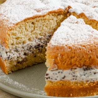 A close up of the easy cassata cake on a serving platter with a slice cut a part from it.