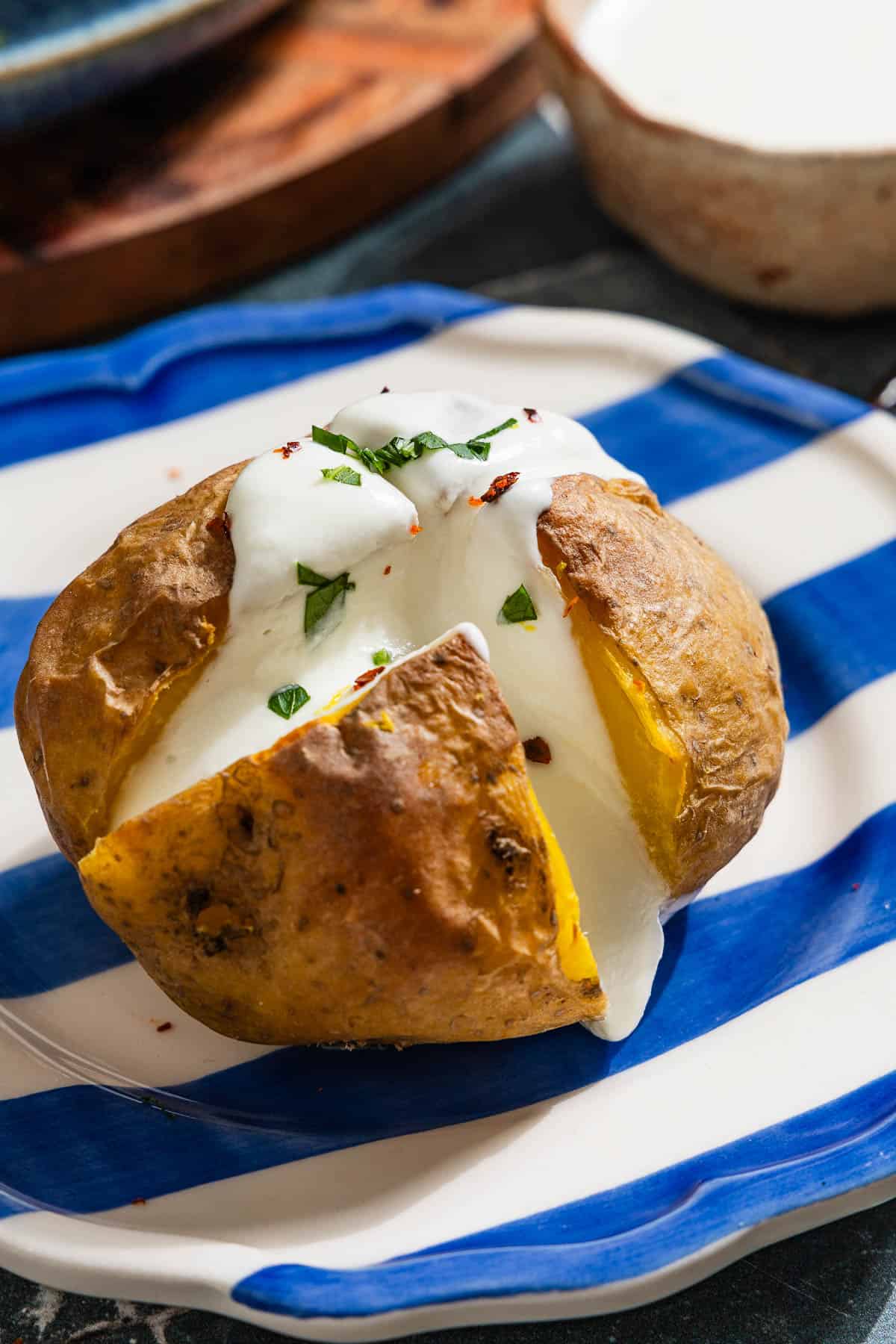 A close up of a stuffed potato with feta on a plate.