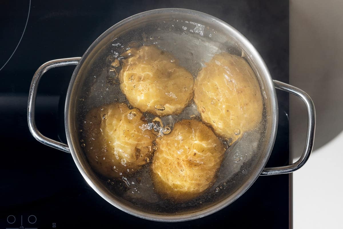 4 potatoes boiling in a pot.