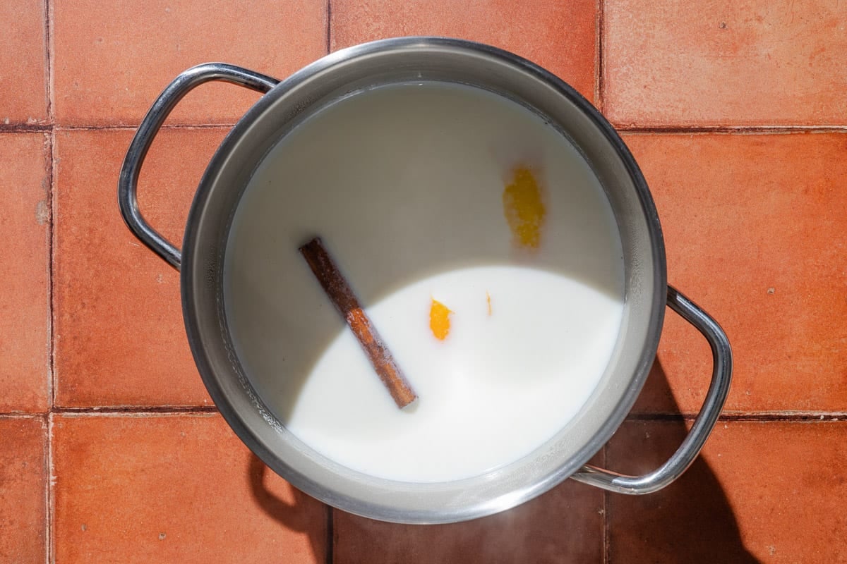 Milk in a pot being infused with honey, sugar, cinnamon and orange peels.