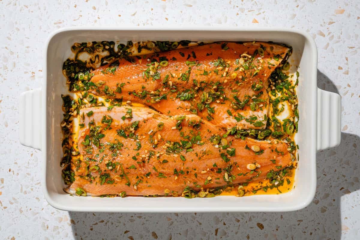 2 Trout fillets marinading in a baking dish.