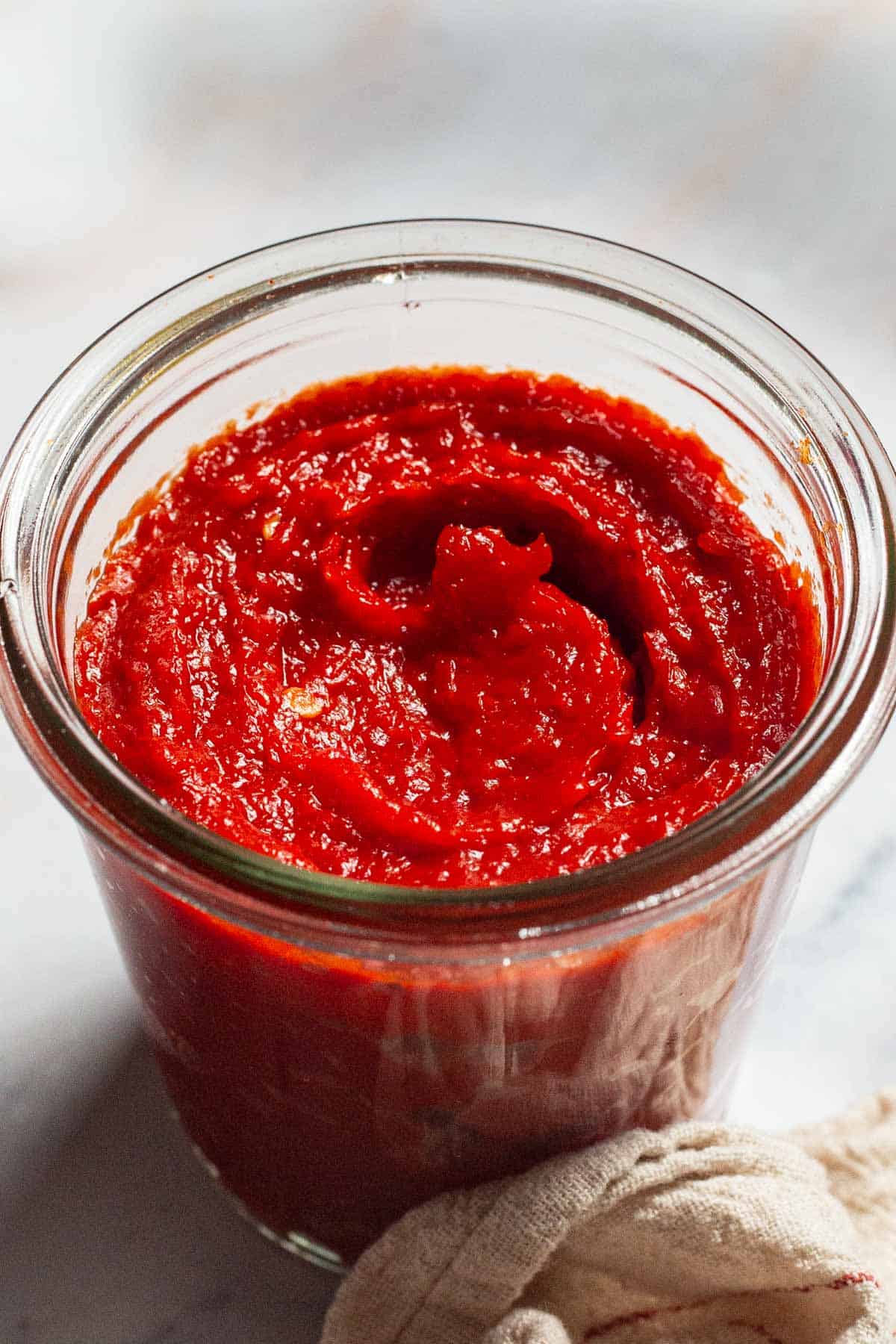 A close up of red pepper paste in a jar.