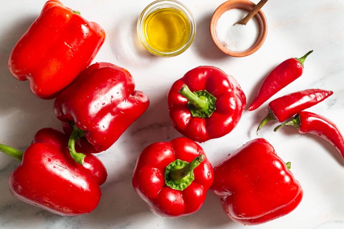 Ingredients for red pepper paste including red bell peppers, red chili peppers, olive oil and salt.