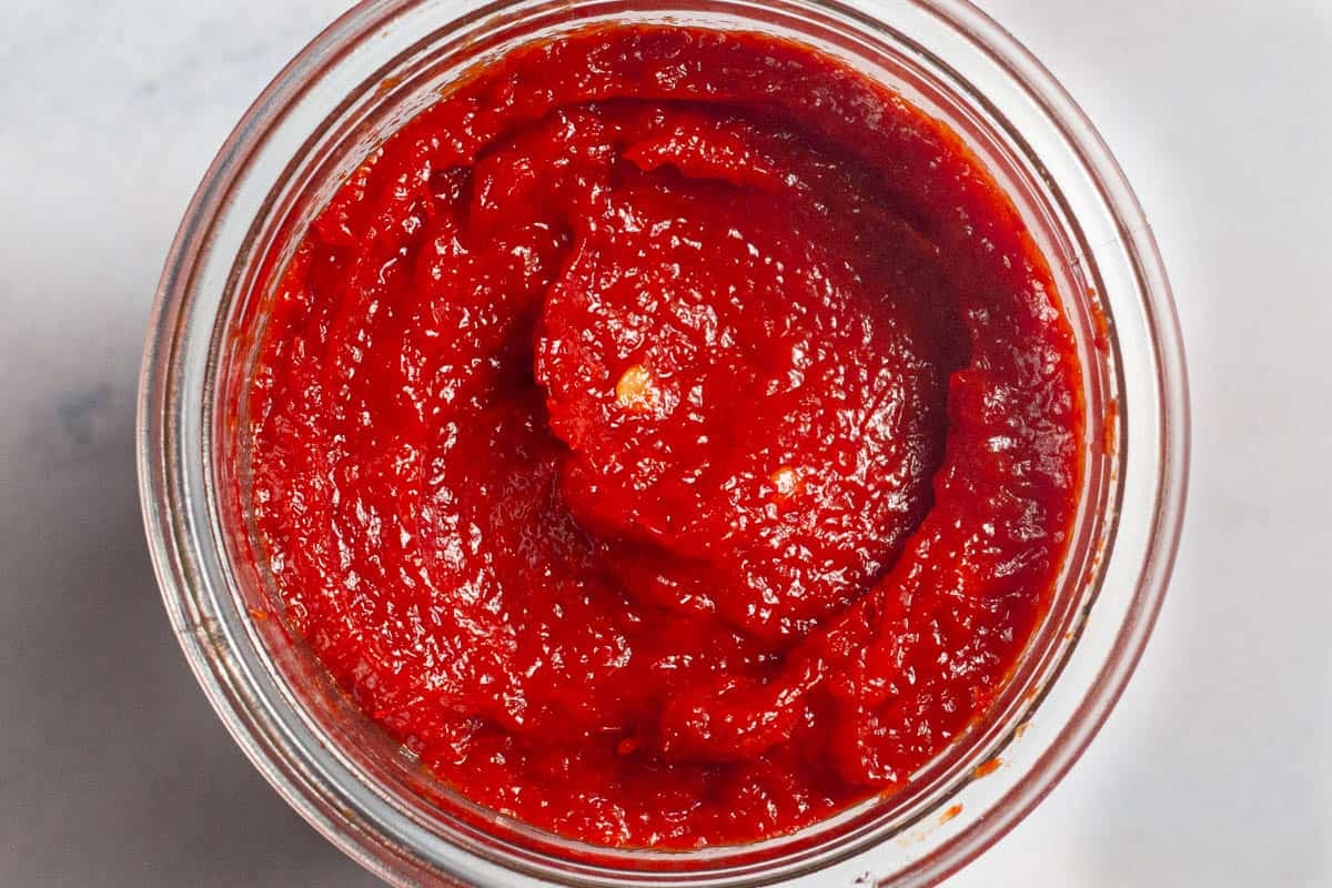 A close up overhead photo of red pepper paste in a jar.