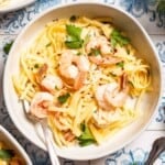 An overhead photo of shrimp linguine in a bowl with a fork .