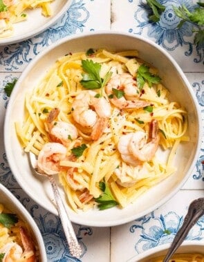 An overhead photo of shrimp linguine in a bowl with a fork .