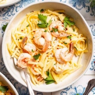 An overhead photo of shrimp linguine in a bowl with a fork .