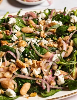 A close up of the wilted spinach salad on a serving platter.