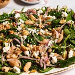 A close up of the wilted spinach salad on a serving platter.