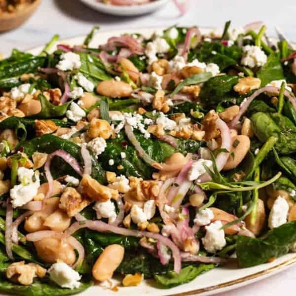 A close up of the wilted spinach salad on a serving platter.