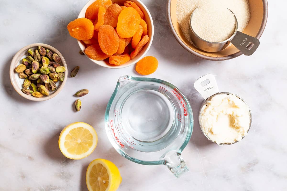 Ingredients for turkish stuffed apricots including dried apricots, sugar, water, lemon, ricotta, and pistachios.