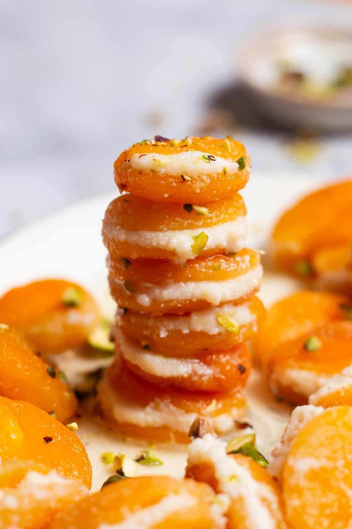 Six stuffed apricots stacked on top of each other on the serving platter with the rest of the stuffed apricots.