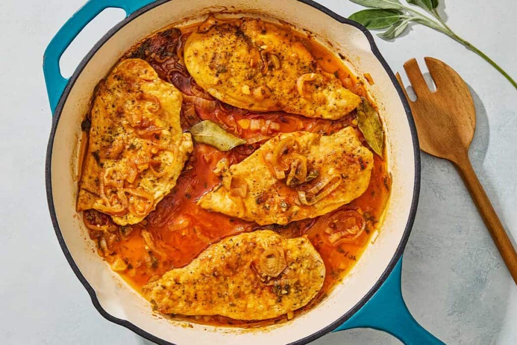 An overhead photo of braised chicken breasts in a skillet.