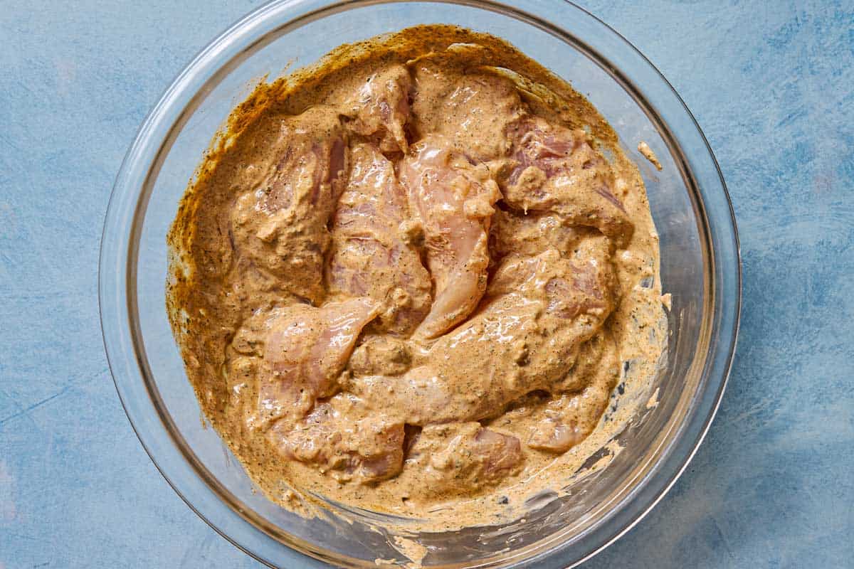 An overhead photo of chicken tenderloins marinating in a large bowl.