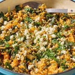 A close up of spanakorizo (Greek spinach rice) in a skillet with a serving spoon.