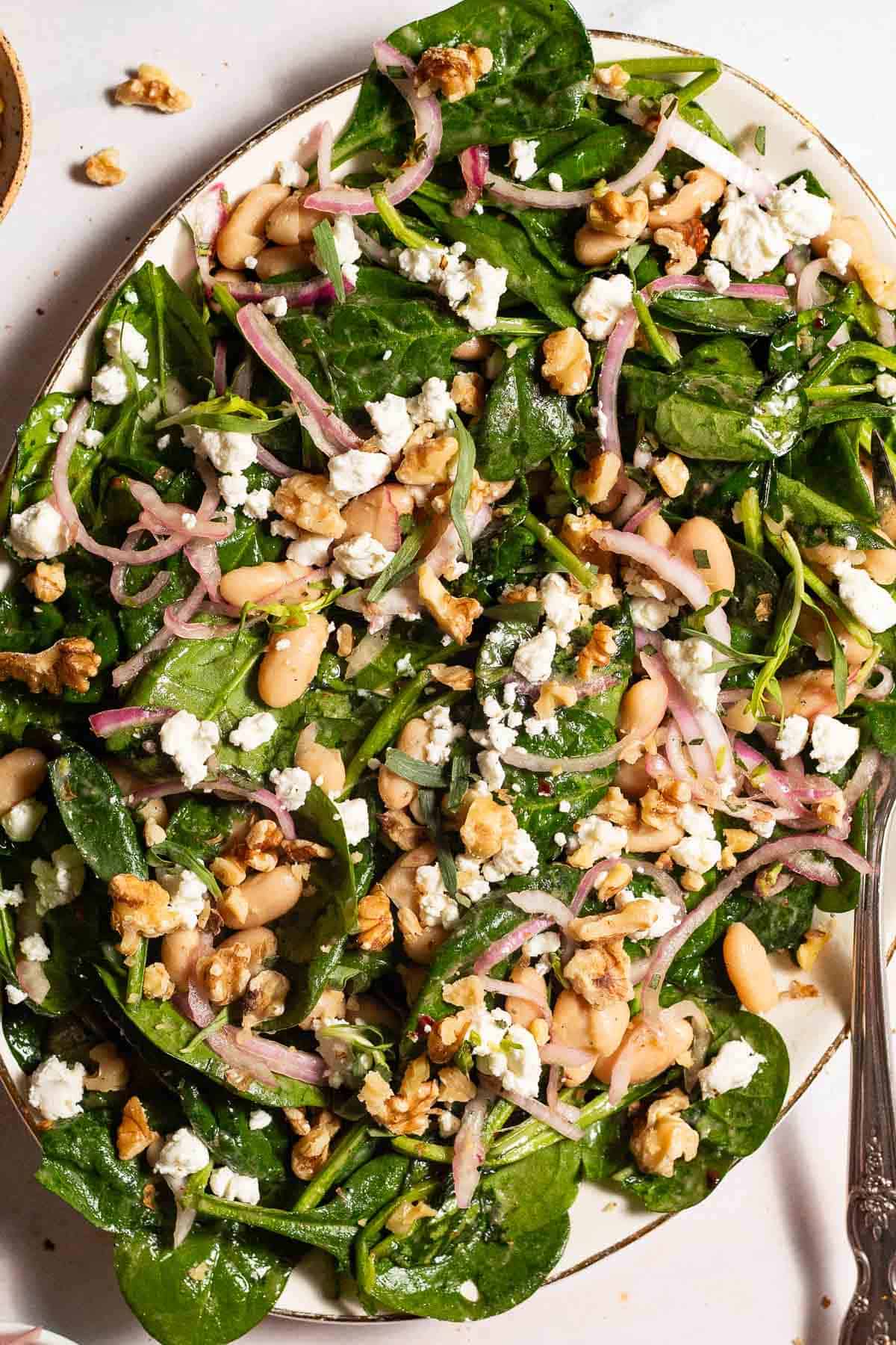 An overhead photo of the wilted spinach salad on a serving platter with a fork.