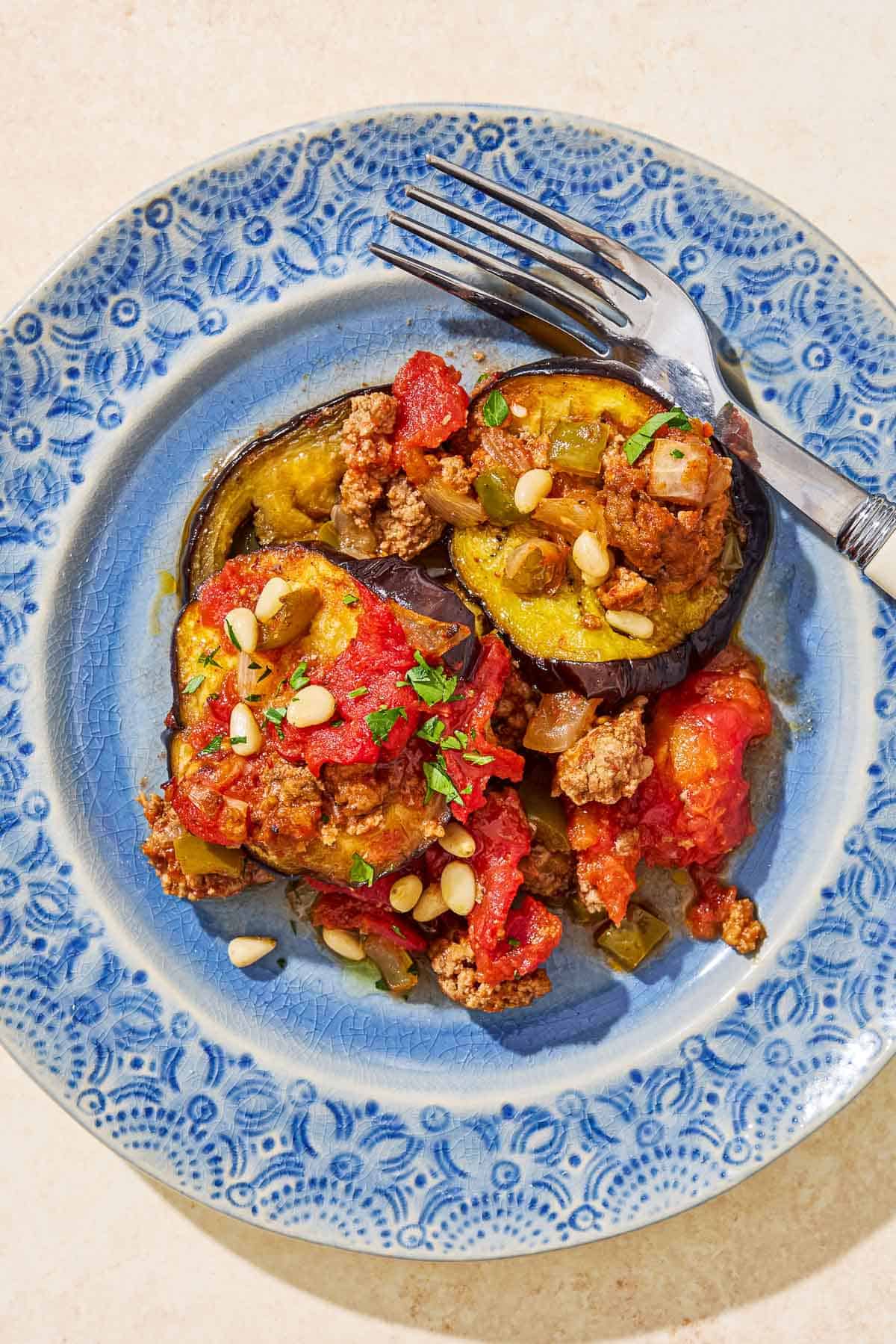 An overhead photo of a serving of egyptian moussaka on a plate with a fork.