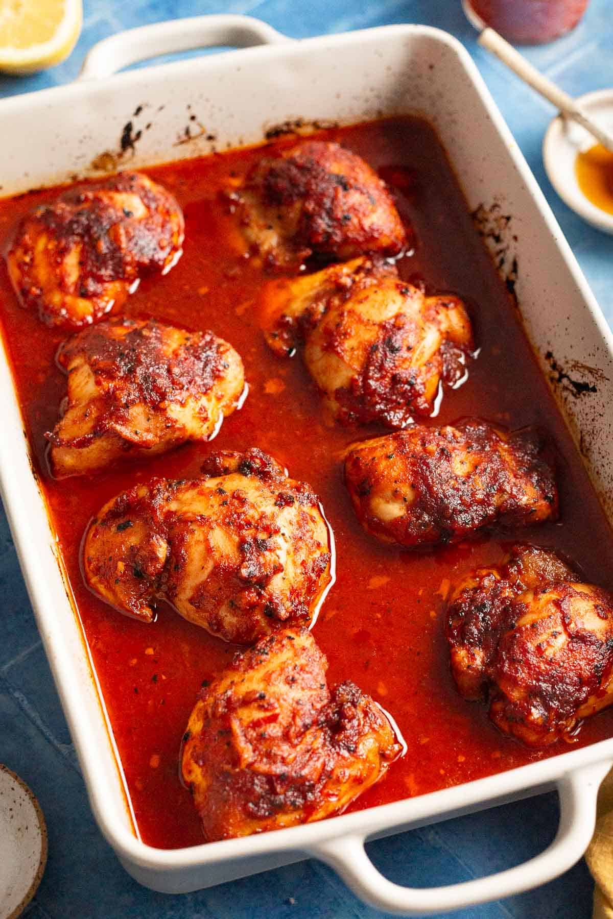 Chicken thighs after baking in a honey harissa sauce, showing the juicy baking dish.