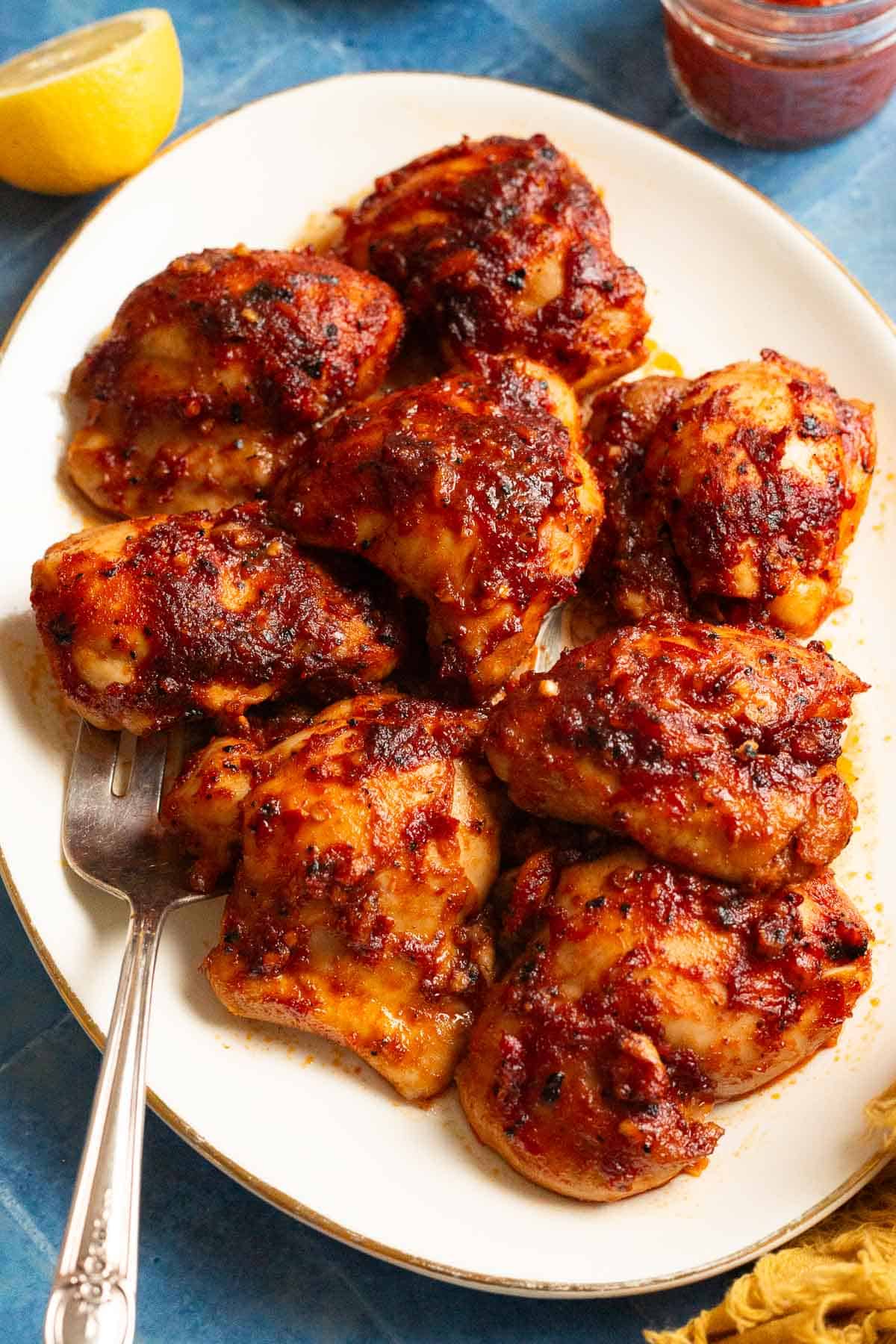 Platter of harissa honey chicken with a silver serving fork.